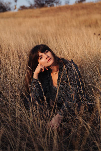 istock Beautiful Young Woman Enjoying the Sunlight While Sitting in High Grass 1305860177