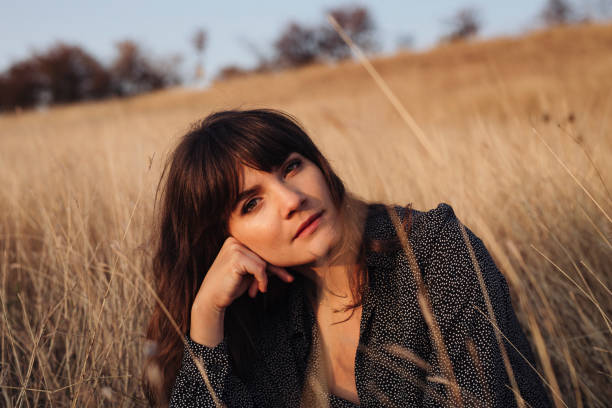 istock Beautiful Young Woman Enjoying the Sunlight While Sitting in High Grass 1305860178