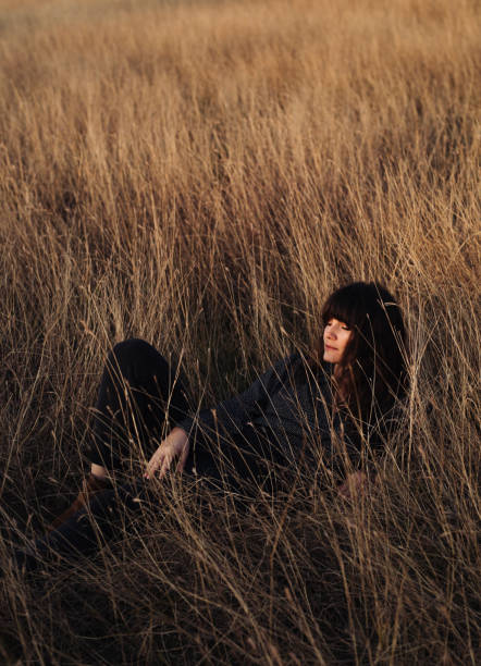 istock Beautiful Young Woman Enjoying the Sunlight While Lying in High Grass 1305860184