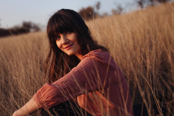 istock Beautiful Young Woman Enjoying the Sunlight While Sitting in High Grass 1305860191