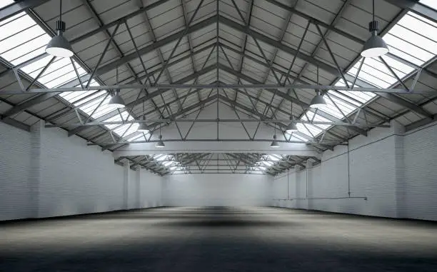 Front view of an empty large warehouse interior with white brick side walls and rough floor illuminated by natural light  from ceiling lights and large roof windows. 3D rendered image.