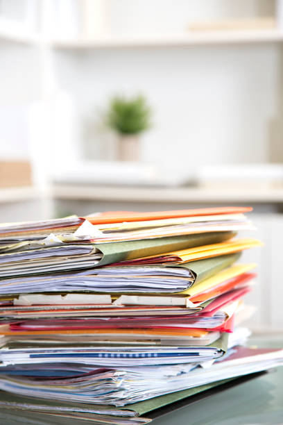 istock Stack of file folders with documents on a glass top desk. 1305861646