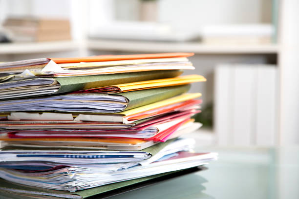 istock Stack of file folders with documents on a glass top desk. 1305861653