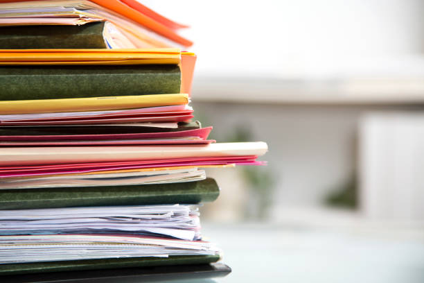 istock Stack of file folders with documents on a glass top desk. 1305861656