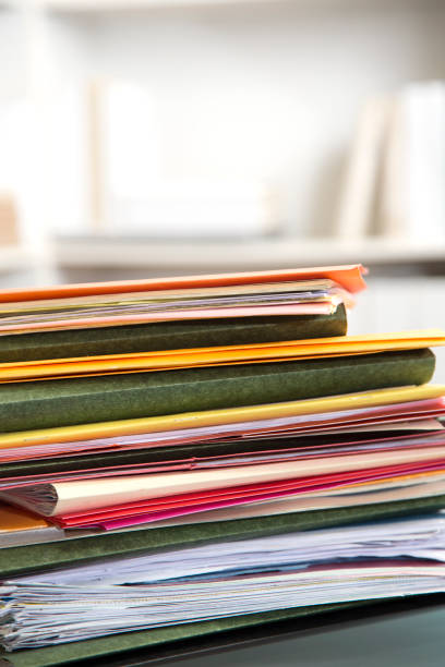 istock Stack of file folders with documents on a glass top desk. 1305861666