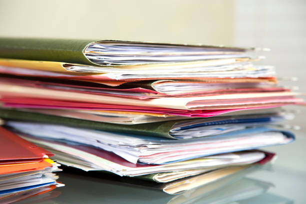 istock Stack of file folders with documents on a glass top desk. 1305861715