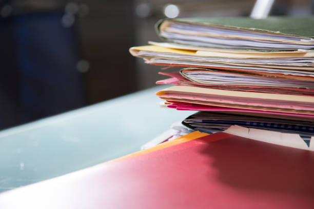 istock Stack of file folders with documents on a glass top desk. 1305861739