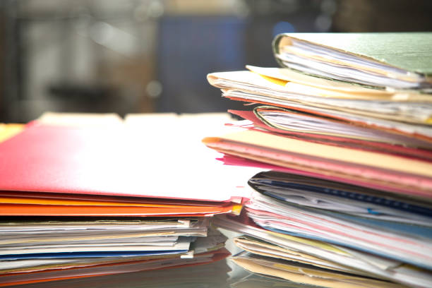 istock Stack of file folders with documents on a glass top desk. 1305861743