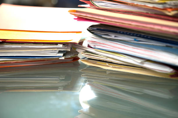 istock Stack of file folders with documents on a glass top desk. 1305861747
