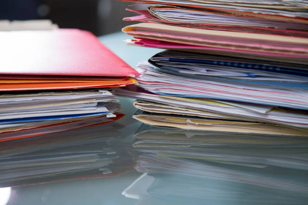 istock Stack of file folders with documents on a glass top desk. 1305861748