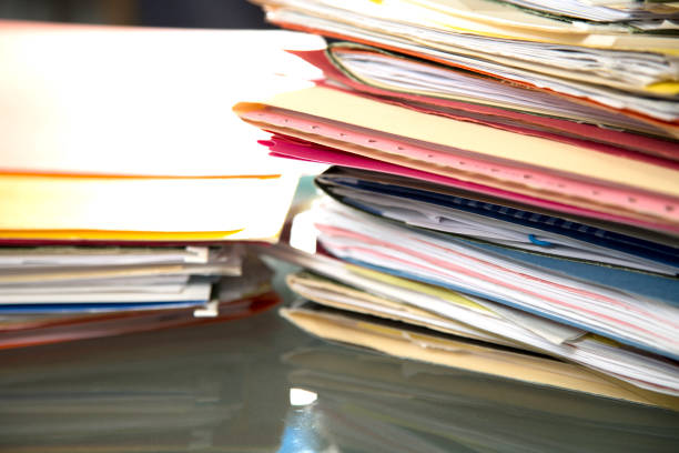 istock Stack of file folders with documents on a glass top desk. 1305861767