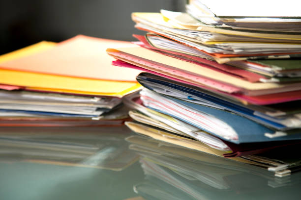 istock Stack of file folders with documents on a glass top desk. 1305861768