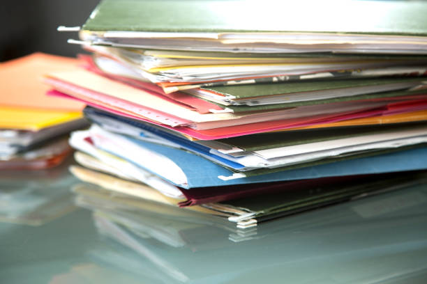 istock Stack of file folders with documents on a glass top desk. 1305861770