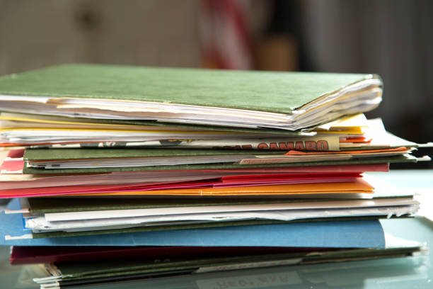 istock Stack of file folders with documents on a glass top desk. 1305861789