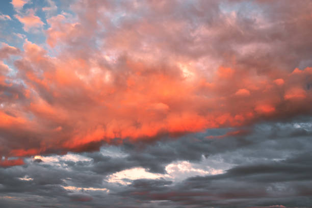 Red clouds lit by the sun over dark gray clouds, full frame