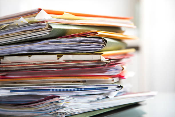 istock Stack of file folders with documents on a glass top desk. 1305862356
