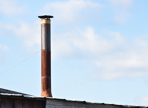 A stove pipe exhaust on top of an abandoned barn.