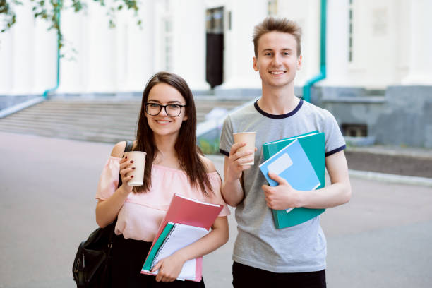 istock Young students with coffee and learning materials during break in front of university 1305866543