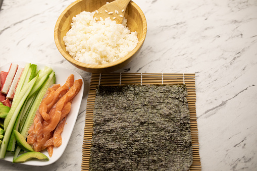 Home sushi preparation, seaweed, cooked rice, salmon and vegetables