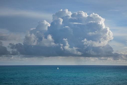 Rain cloud over the ocean horizon with sailboat in Miami Florida.