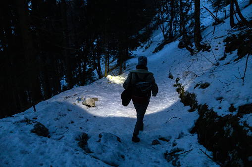 Rear view of Hiker descending in late blue hour with headlamp on in Julian Alps.