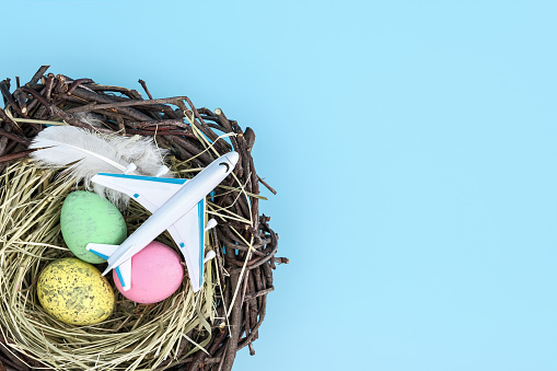 Top view of airplane and easter egg nest flatlay. Spring season travel concept background. Copy space for text
