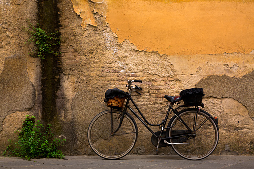 Old, vintage bicycle against a weathered, textured wall in Lucca, Italy