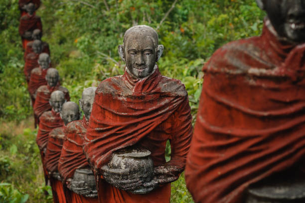 setki starych posągów buddyjskich mnichów zbierających jałmużnę otaczają buddę win sein taw ya w mawlamyine, myanmar (birma) - reclining buddha zdjęcia i obrazy z banku zdjęć