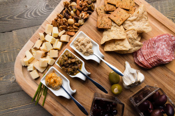 istock Wooden cutting board with a selection of crackers, cheeses and dips 1305874736