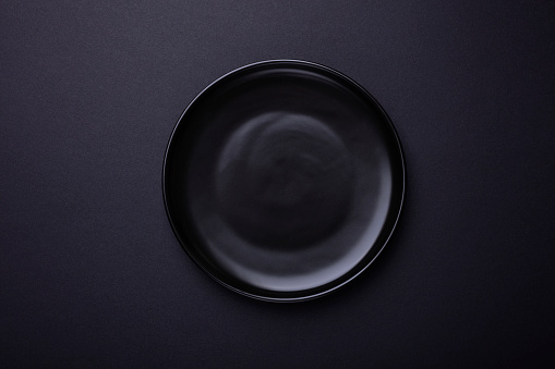 Empty black plate on black background with clipping Path. Top view.