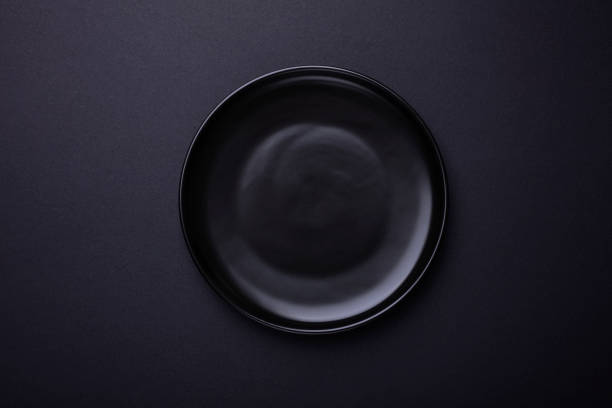 Empty black plate on black background with clipping Path. Top view. stock photo