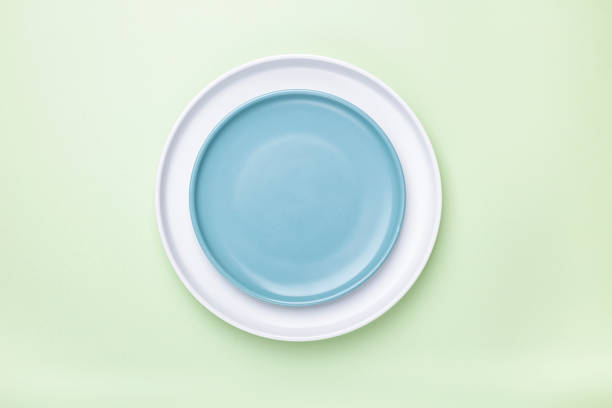 istock Empty white and blue plates on green background with clipping Path. Top view. 1305877144