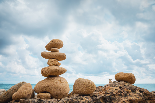 Balancing stones on idyllic Greek beach.