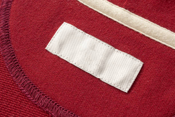 пустой белый прачечная одежды этикетки на красной ткани текстуры фона - label textile shirt stitch стоковые фото и изображения