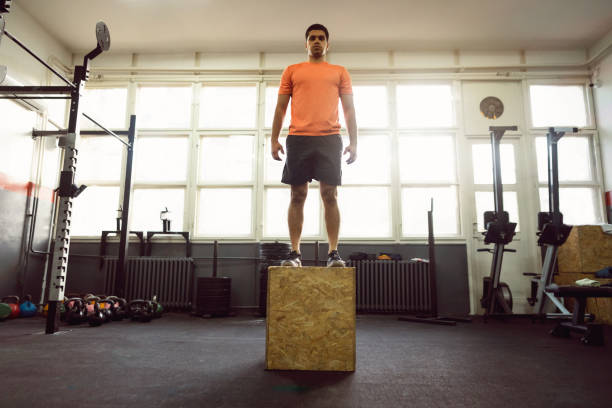 istock Young man doing box jump in gym 1305883546