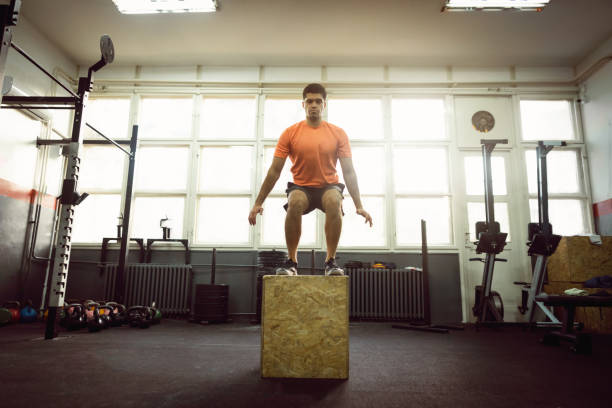istock Young man doing box jump in gym 1305883548