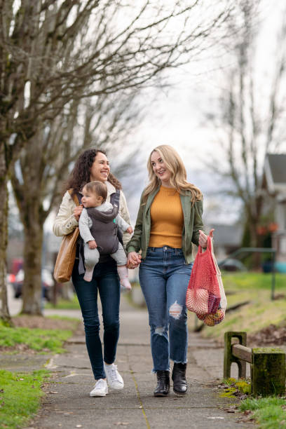 coppia femminile dello stesso sesso che si tiene per mano mentre fa una passeggiata con la bambina - alternative health care foto e immagini stock