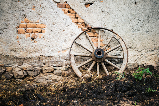 Old wooden wagon wheel on an old wall background. Rural concept.