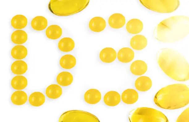 Small Vitamin D3 capsules forming letter D and number 3, with Omega-3 capsules around isolated on white