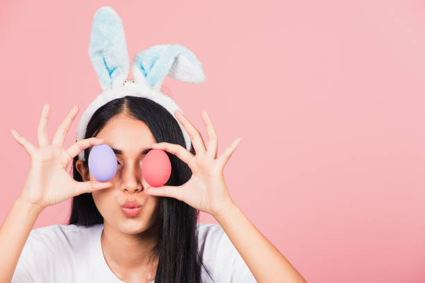 istock woman smiling wearing rabbit ears holding colorful Easter eggs front eyes 1305897881