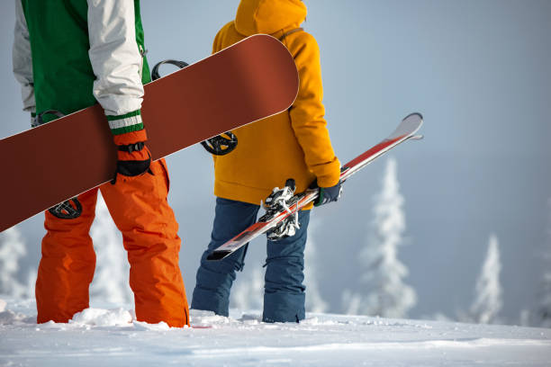 la coppia di sciatori e snowboarder non riconosciuta si trova in cima alla montagna - tavola da snowboard foto e immagini stock