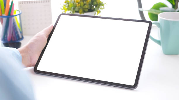 istock Close up of man hand holding digital tablet with blak screen on working table background for mock up, template 1305904650