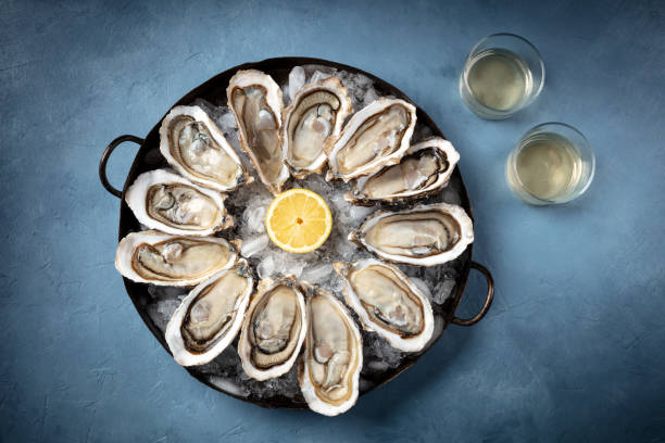 istock Oysters on ice, lemon, and white wine, overhead flat lay shot 1305905452