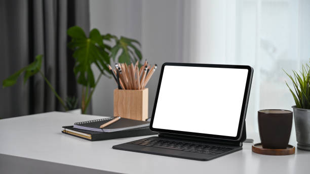 istock Comfortable workplace with computer tablet, notebook, coffee cup and plant on white desk. 1305905622
