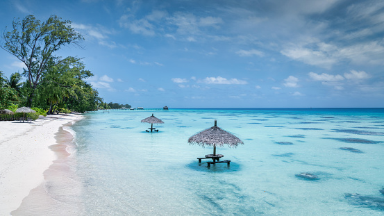 Fakarava Island Lagoon Beach Panorama. Wooden straw parasols and wooden benches at the natural atoll beach inside the beautiful turquoise south pacific ocean lagoon of the Fakarava Atoll Lagoon. Fakarava Island, Havaiki-te-araro - Farea, Tuamotu Archipelago, French Polynesia, Oceania