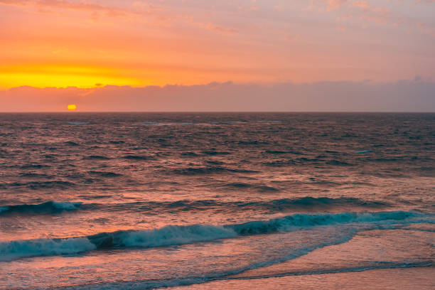 istock Big yellow sun falling behind the sea 1305912834