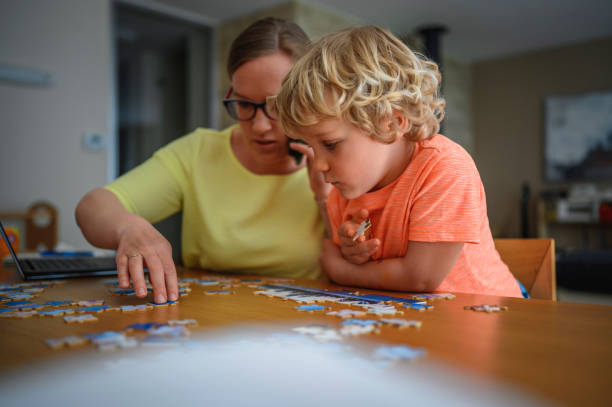 istock Mother working at home and helping son collecting puzzles at the same time 1305914322