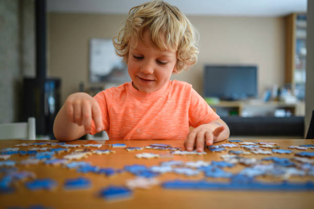 istock Cute blond boy collecting puzzles on the table 1305914327