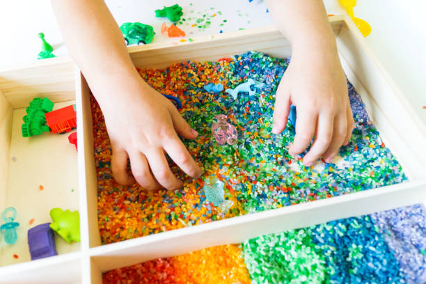 istock Sensory box with rainbow rice inside. Montessori material baby 1305914927