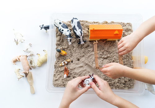 Children's hands play an animal figure. Kinetic sand